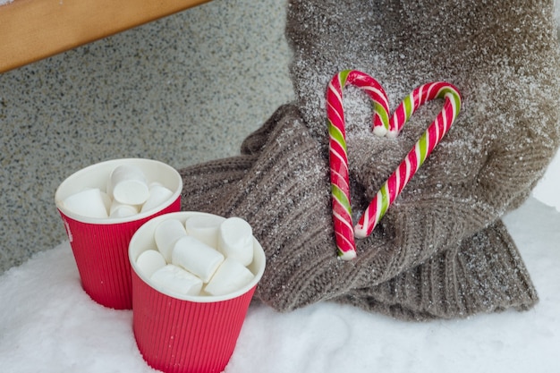 Dos tazas de café con malvavisco, dos bastones de caramelo navideño.