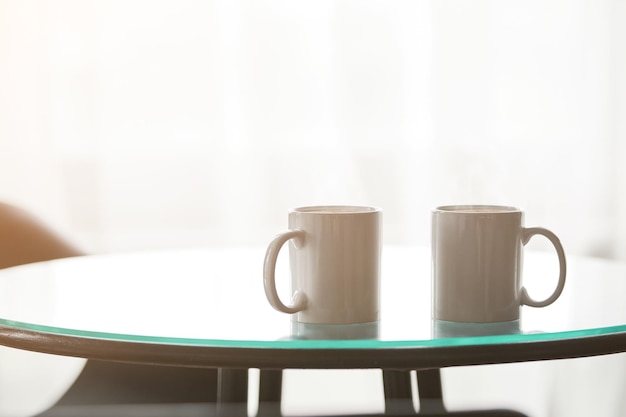 Dos tazas de café en una mesa de cristal