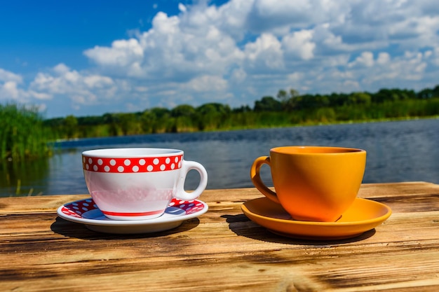 Dos tazas de café en la mesa de madera rústica en la orilla del río