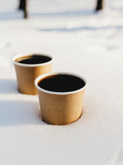 Dos tazas de café en la nieve del bosque.