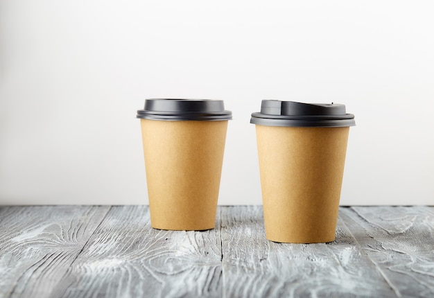 Dos tazas de café de papel para llevar sobre fondo de madera gris