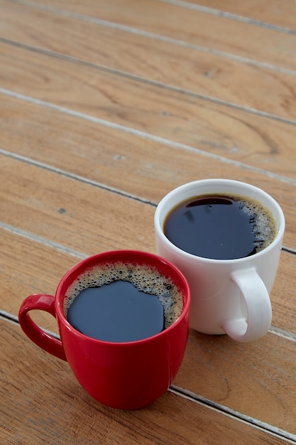 Dos tazas de café rojo y blanco en madera