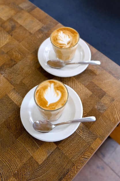 Dos tazas de café sobre fondo rústico negro con hermoso arte latte