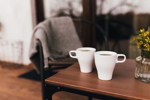 Dos tazas de café sobre la mesa en la terraza de madera marrón durante el atardecer. Relajación, concepto de vida en el campo silencioso. Encantadoras tardes de pareja