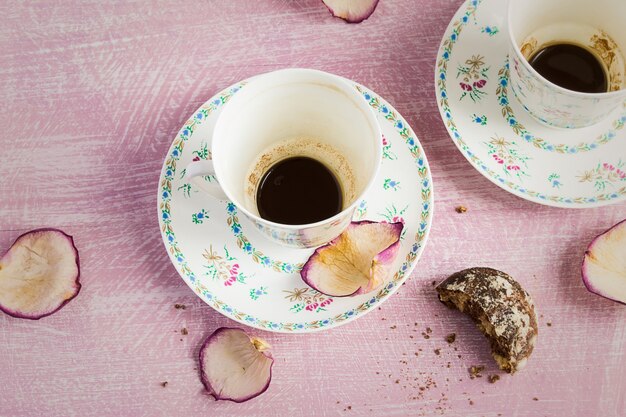 Dos tazas de café vacías y pétalos de rosa.