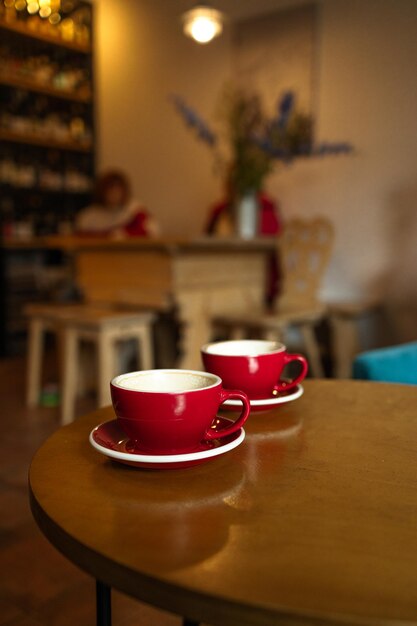 Dos tazas de capuchino con arte latte en fondo de madera hermosa espuma tazas de cerámica roja alta