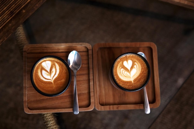 Dos tazas de capuchino caliente sobre fondo de escritorio de madera