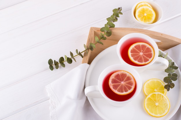 Dos tazas de frutos rojos y té de hierbas con rodaja de limón, vista superior