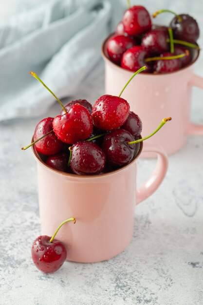 Dos tazas rosas con cerezas maduras frescas