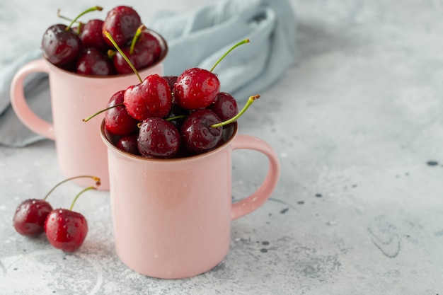 Dos tazas rosas con cerezas maduras frescas