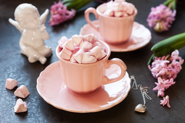 Dos tazas rosas con malvaviscos en forma de corazón