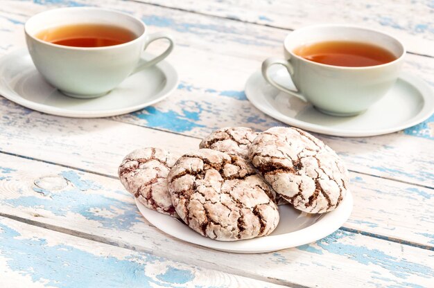 Dos tazas de té y platillo con galletas en la mesa de madera antigua