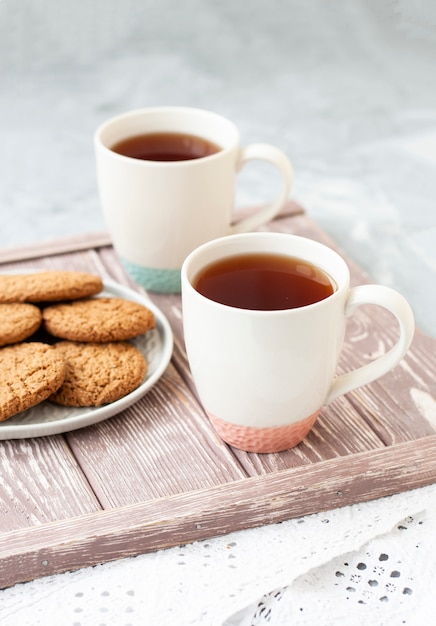 Dos tazas de té y un plato de galletas.