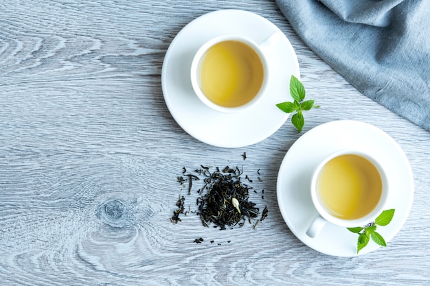 Dos tazas de té verde en una mesa gris