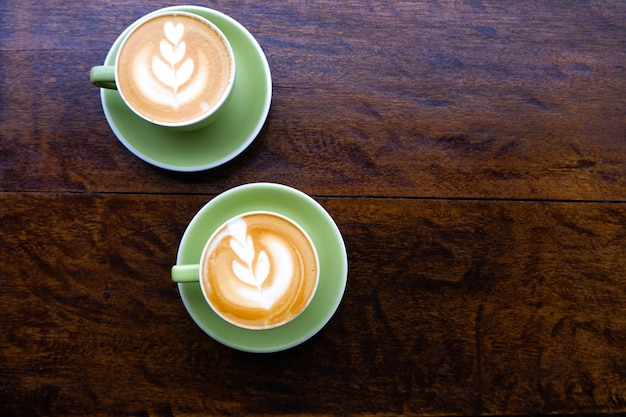 Dos tazas verdes de capuchino con arte latte en mesa de madera