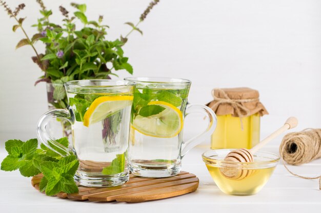 Dos tazas de vidrio de té de menta fresca con limón y un montón de menta en florero