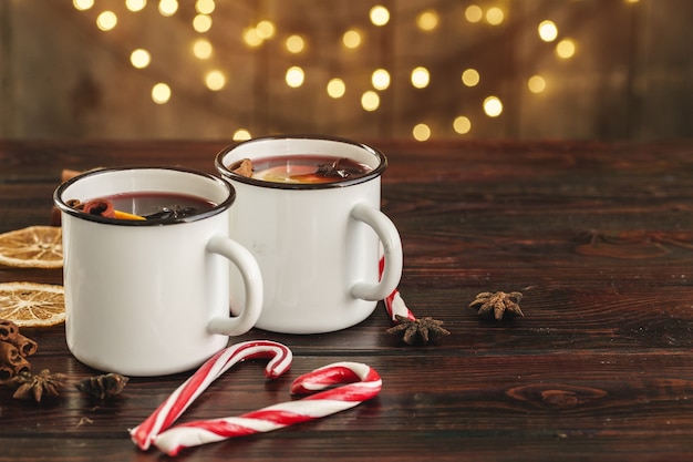 Dos tazas de vino caliente navideño sobre una mesa de madera