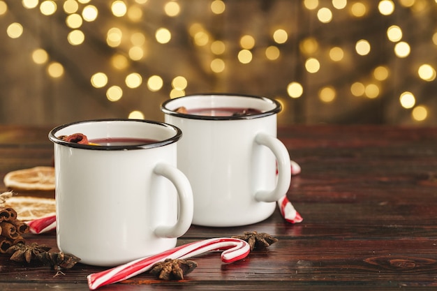 Dos tazas de vino caliente navideño sobre una mesa de madera