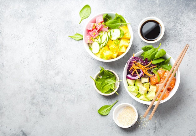 Dos tazones de fuente surtidos con pescado crudo y verduras, espacio para texto. Vista superior. Plato tradicional hawaiano, fondo de piedra rústica. Concepto de alimentación saludable y limpia. Empuje con rodajas de pescado crudo, espacio de copia