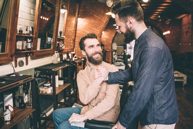 Foto dos tipos se dan la mano. están felices de encontrarse en una barbería.