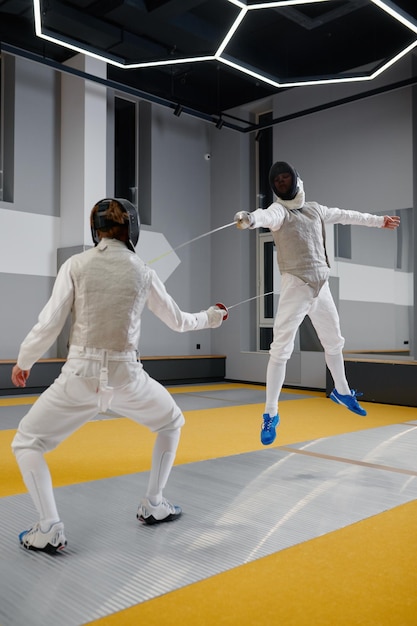 Dos tiradores entrenando durante una sesión de entrenamiento en una escuela profesional de artes marciales. Espadachín saltando tratando de esquivar un ataque