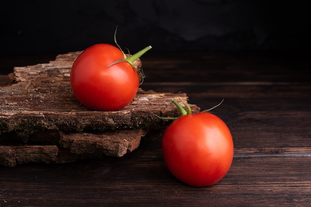 Dos tomates frescos rojos en mesa de madera y mesa de madera oscura.