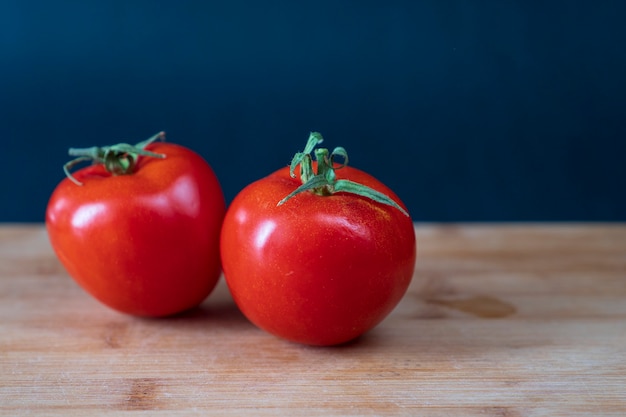 Dos tomates orgánicos en mesa de madera