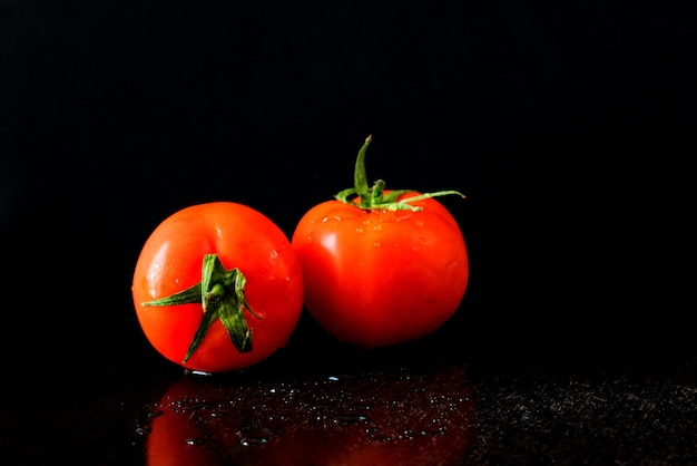 Dos tomates sobre un fondo negro