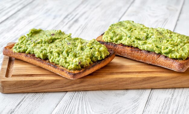 Dos tostadas con guacamole en tabla de cortar