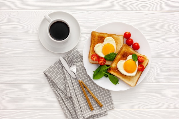 Dos tostadas con huevos revueltos en forma de corazón en un plato