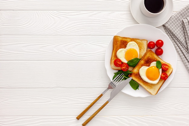 Dos tostadas con huevos revueltos en forma de corazón en un plato