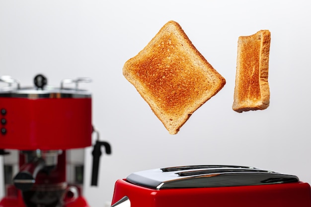 Dos tostadas saltando de la tostadora roja contra un fondo blanco