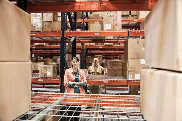 Dos trabajadores de almacén entre estantes de productos en caja en estantes en un almacén