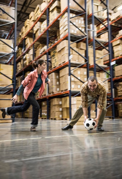 Dos trabajadores de almacén jugando al fútbol durante un descanso en un almacén de distribución