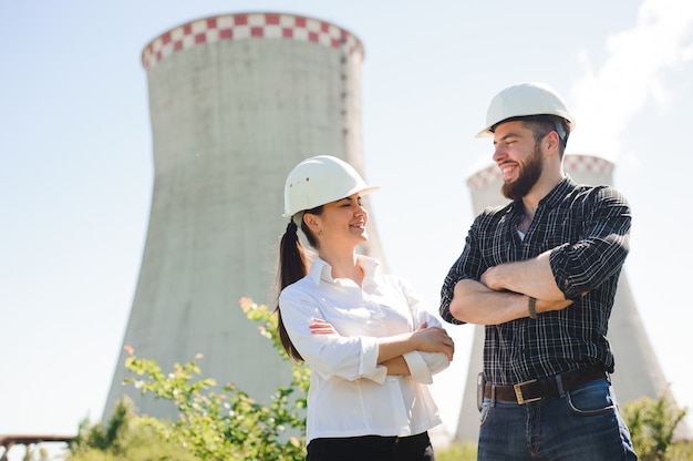 Dos trabajadores con casco protector trabajan en la estación de energía eléctrica