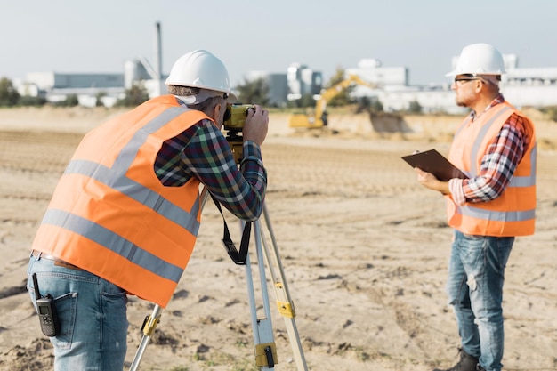 Foto dos trabajadores de la construcción de carreteras que utilizan un dispositivo de medición en el campo