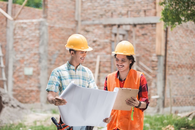 Dos trabajadores de la construcción de pie frente a la obra