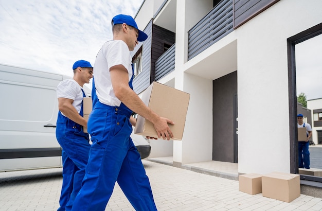 Dos trabajadores de la empresa de mudanzas descargando cajas y muebles del minibús