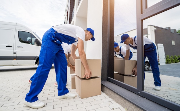 Dos trabajadores de la empresa de mudanzas descargando cajas y muebles del minibús