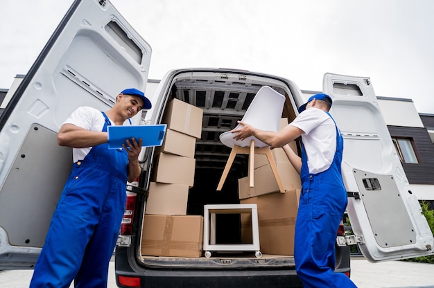 Foto dos trabajadores de la empresa de mudanzas descargando cajas y muebles del minibús