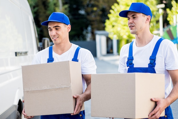 Dos trabajadores de la empresa de mudanzas están cargando cajas en un minibús