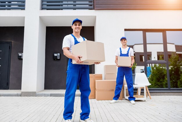 Dos trabajadores de la empresa de mudanzas están cargando cajas en un minibús