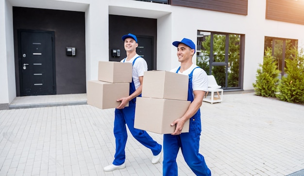 Dos trabajadores de la empresa de mudanzas están cargando cajas en un minibús