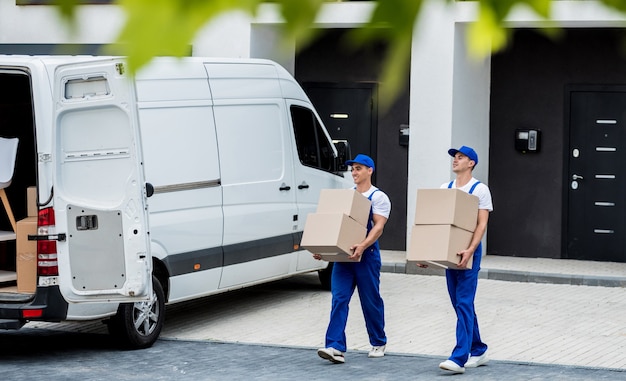 Dos trabajadores de la empresa de mudanzas están cargando cajas y muebles en un minibús