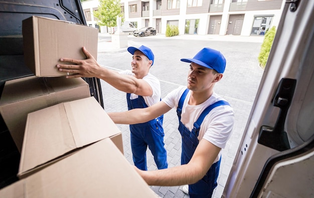 Dos trabajadores de la empresa de mudanzas están cargando cajas y muebles en un minibús