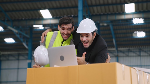 Dos trabajadores de fábrica celebran el éxito juntos en la fábrica o el almacén. Concepto de logro de trabajo de la industria.