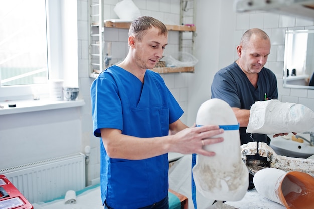 Dos trabajadores ortopédicos haciendo prótesis de pierna mientras trabajaba en laboratorio.