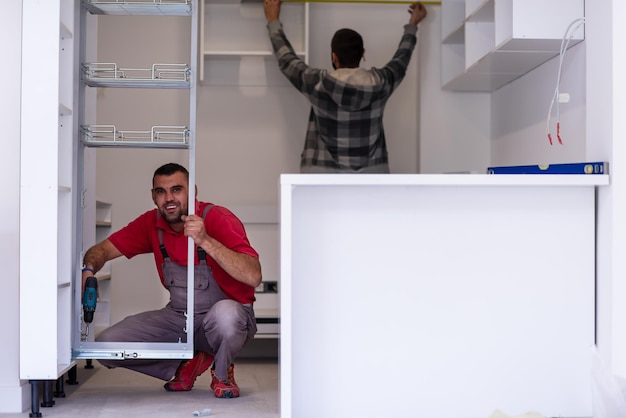 Foto dos trabajadores profesionales instalando un nuevo y elegante mobiliario de cocina moderno.
