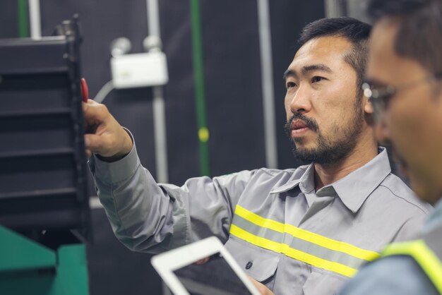 Foto dos trabajadores técnicos con tabletas trabajando en una fábrica de la industria comprobando la planta de la sala de control