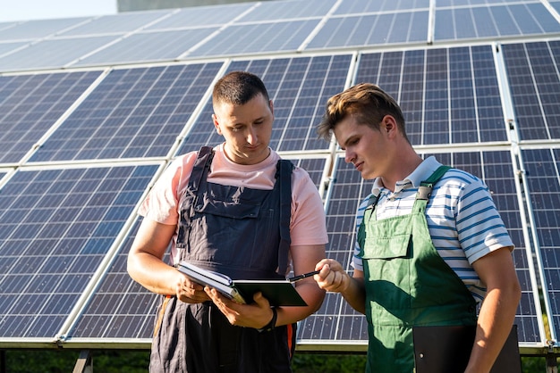 Dos trabajadores uniformados hablan sobre la instalación de paneles solares Energía alternativa